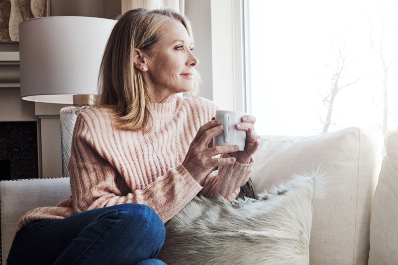 A woman relaxing on her couch drinking coffee
