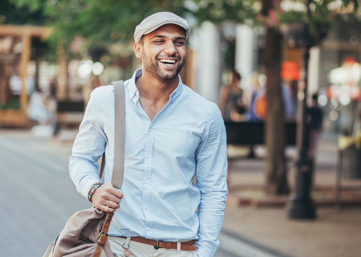 A young man walking and smiling thinking about First Midwest Bank loans, deposits, and charitable giving statistics