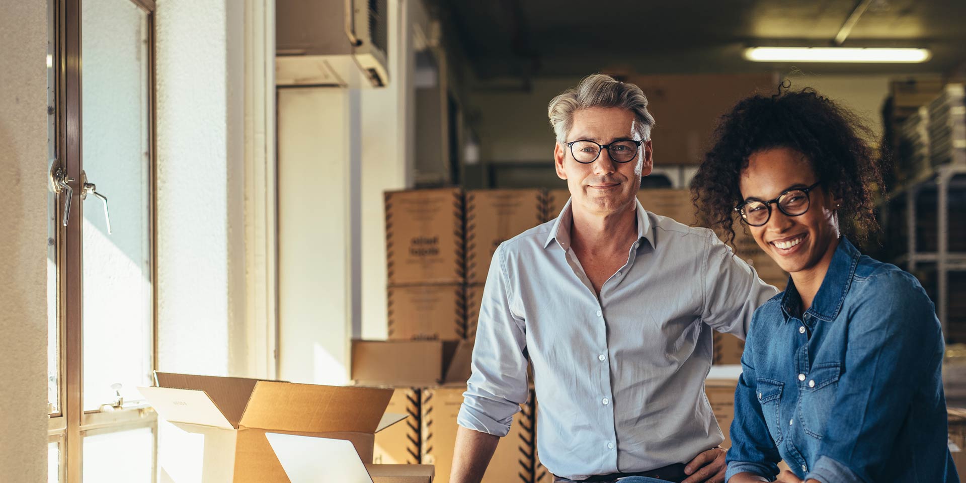 Two business owners with a Business Line of Credit are standing in front of inventory that is ready to be shipped