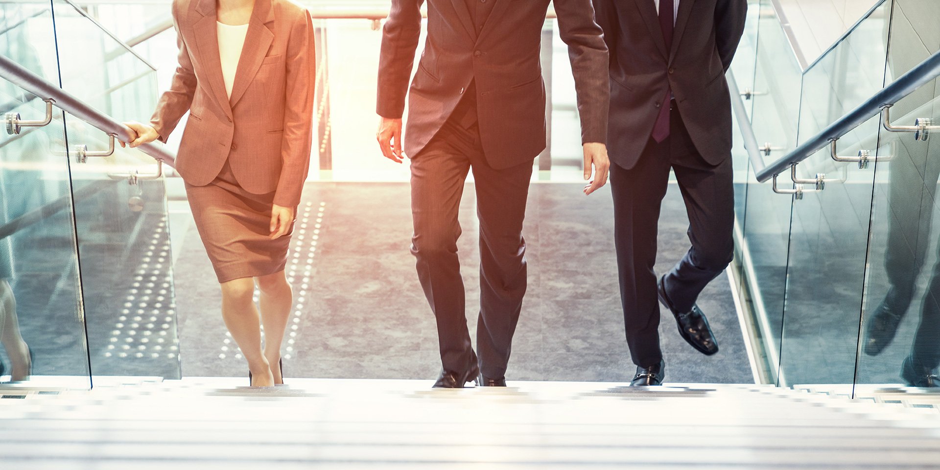 Three members of First Midwest Bank’s Leadership Team are walking up a modern building staircase