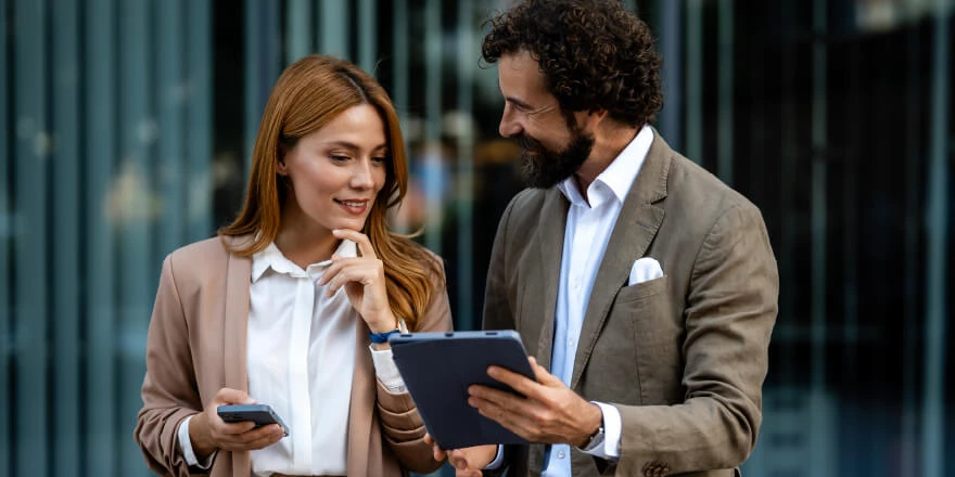 Image of two professionals talking and looking at one tablet