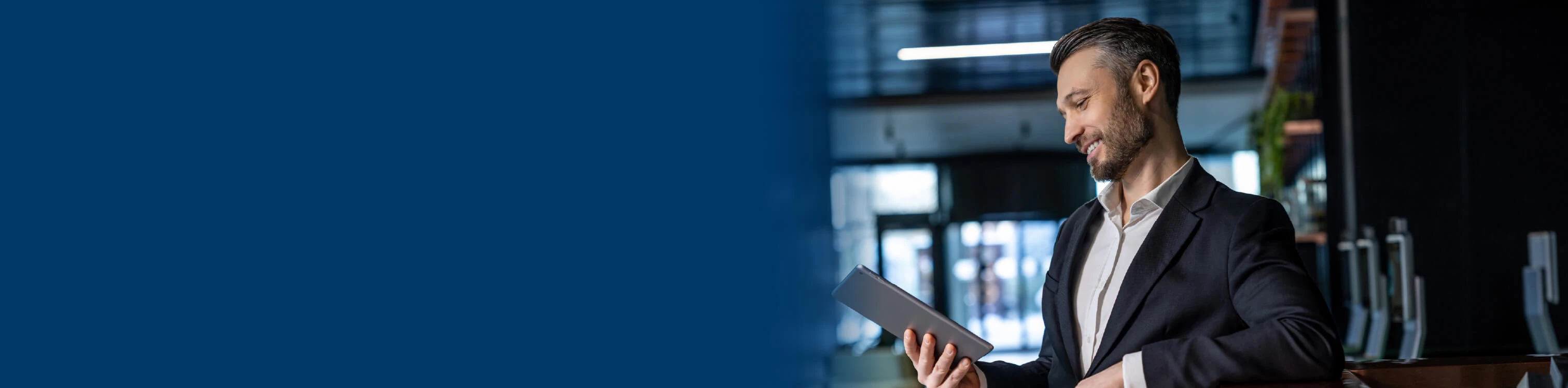 Image of a businessman in an office looking down at his tablet