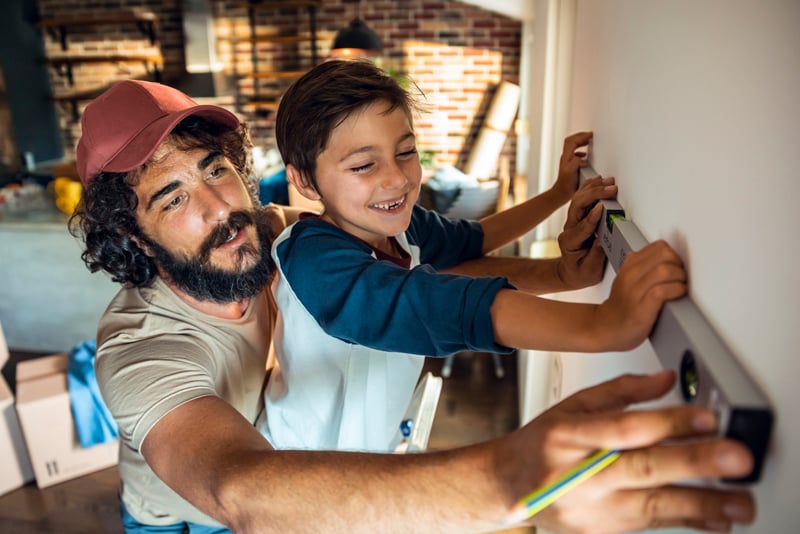 A dad and son holding up a level