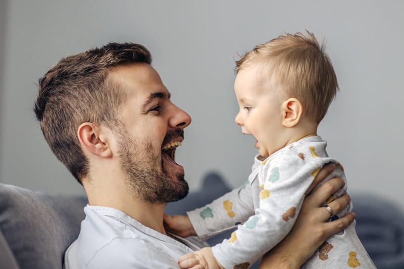 A dad holding his son and smiling