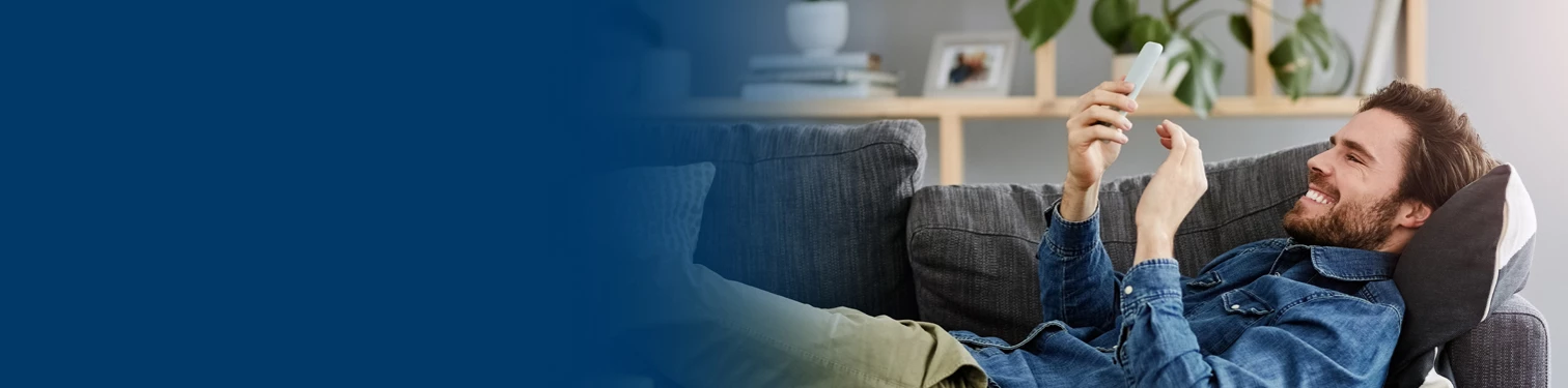A man laying on his couch sending money to his friend