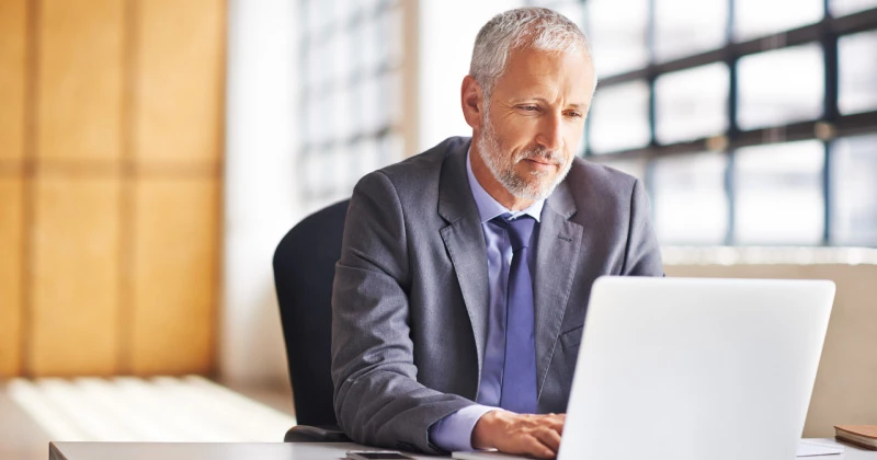 Photo of a businessman sitting in an office looking at a laptop