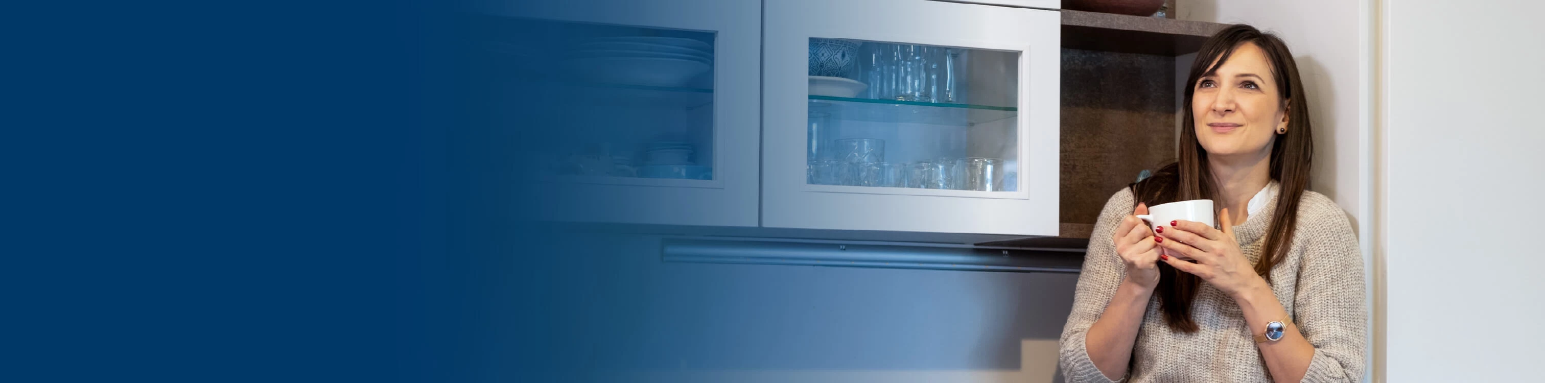A woman in her kitchen drinking coffee