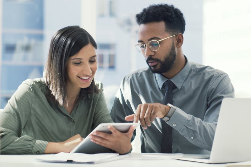 A coworker showing his teammate who to sign up for direct deposit