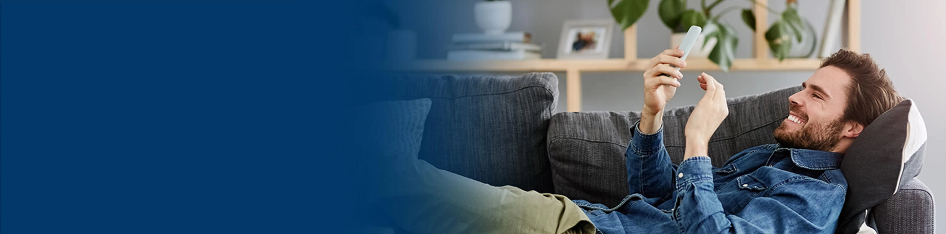 A man laying on his couch sending money to his friend