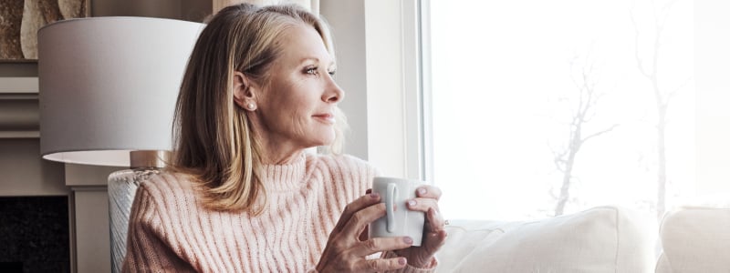 A woman relaxing on her couch drinking coffee