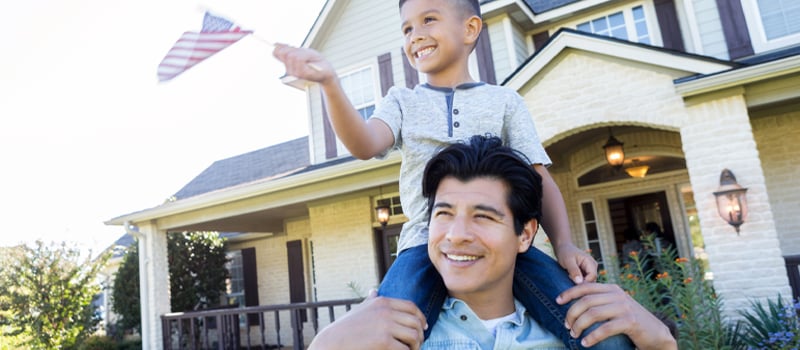 A son outside sitting on his dad's shoulders