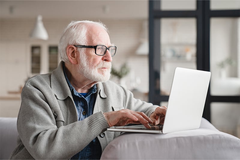 An older man looking at his account information on his laptop