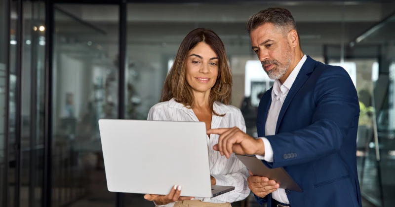 Two colleagues looking at her laptop and realizing how easy it is to enroll in Zelle