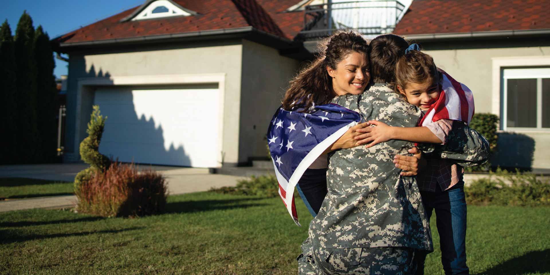 A family hugging outside their new home