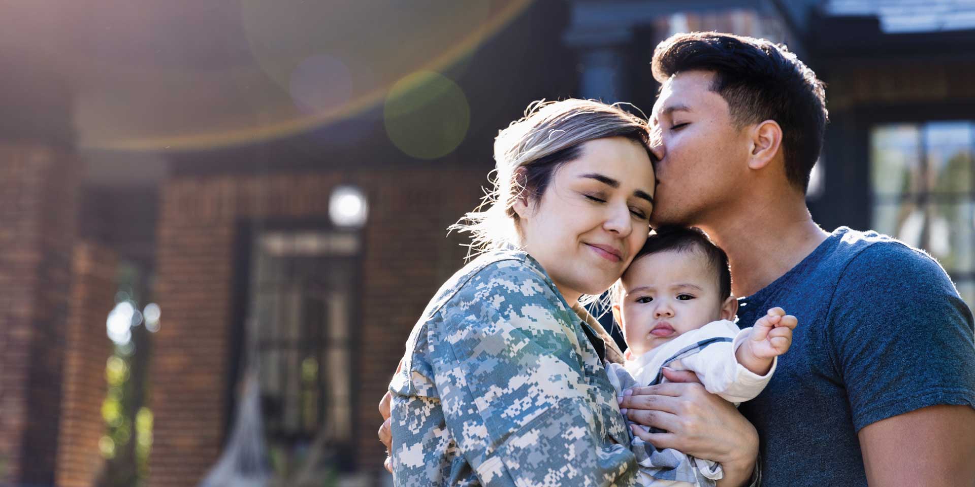 A mom holding her child outside her home