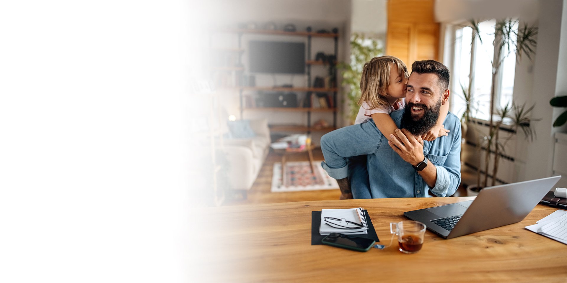 A daughter and her dad hugging at his desk at home