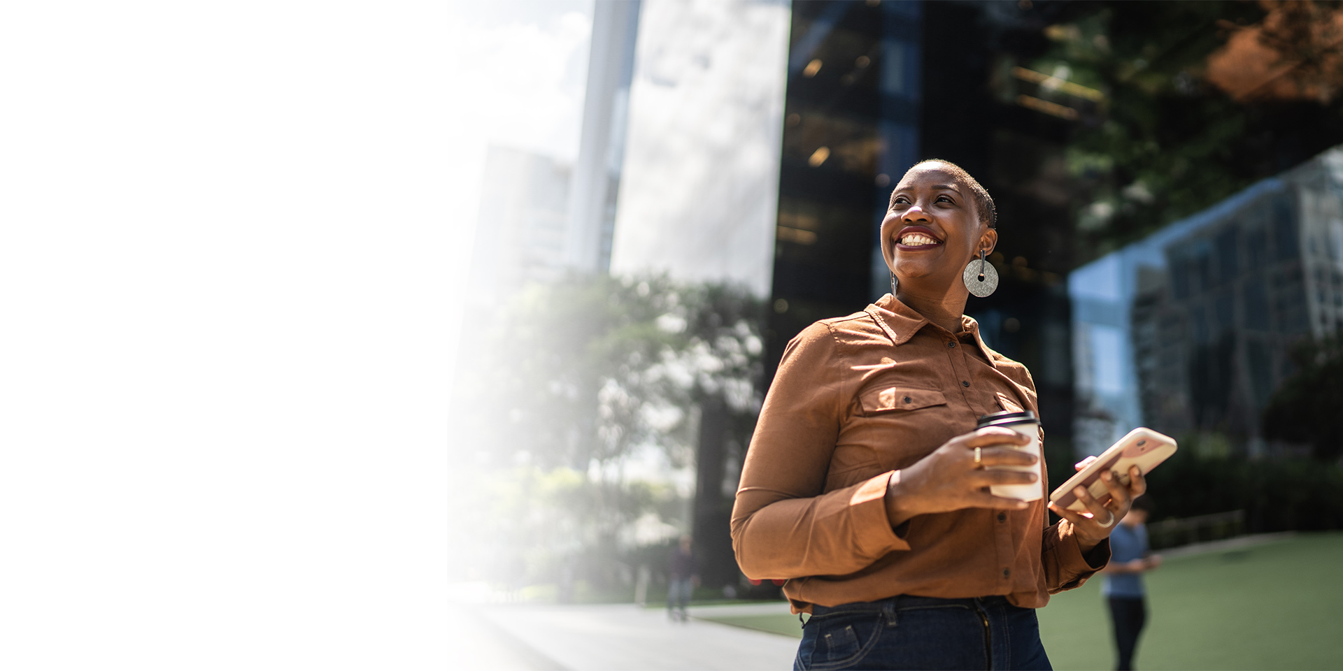 A woman outside her work building holding her mobile device