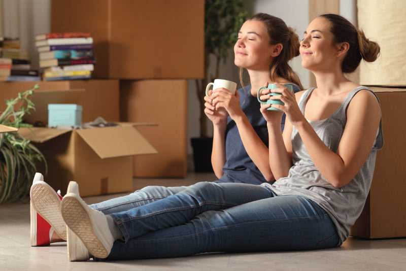 Roommates having a drink before they tackle their moving boxes