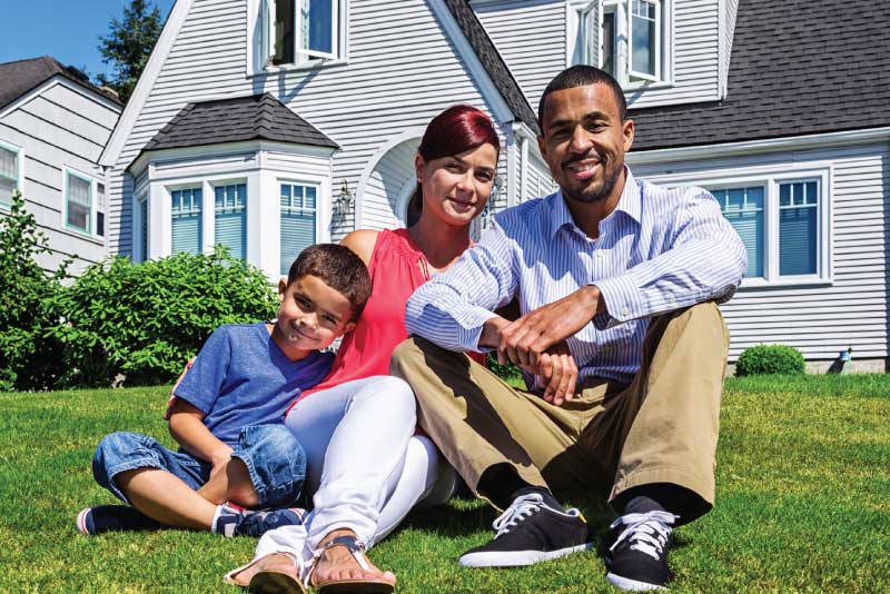 A family outside their home sitting on the lawn