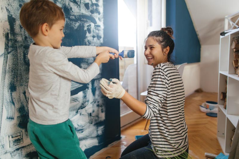 A mom and her son working on painting his new toy room