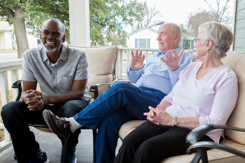 A couple outside on their porch entertaining guests