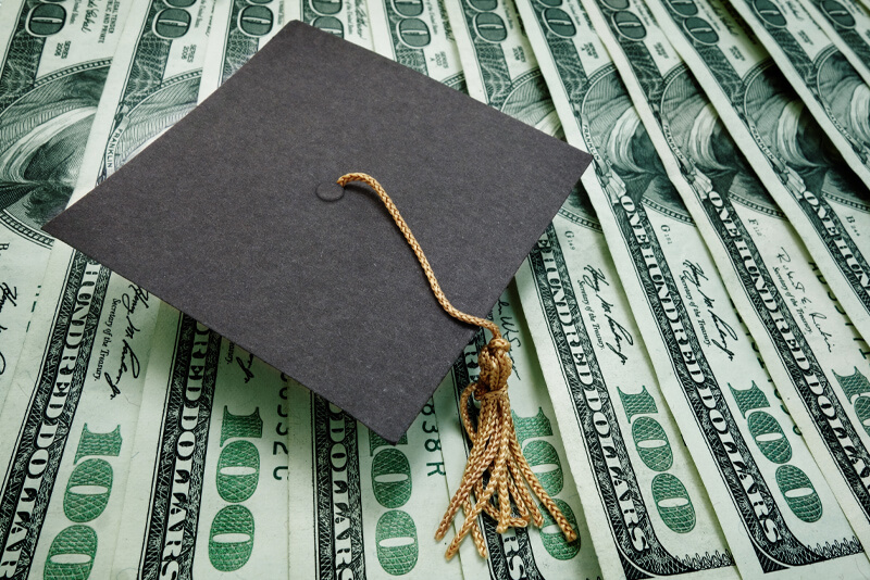 A graduation cap on top of money