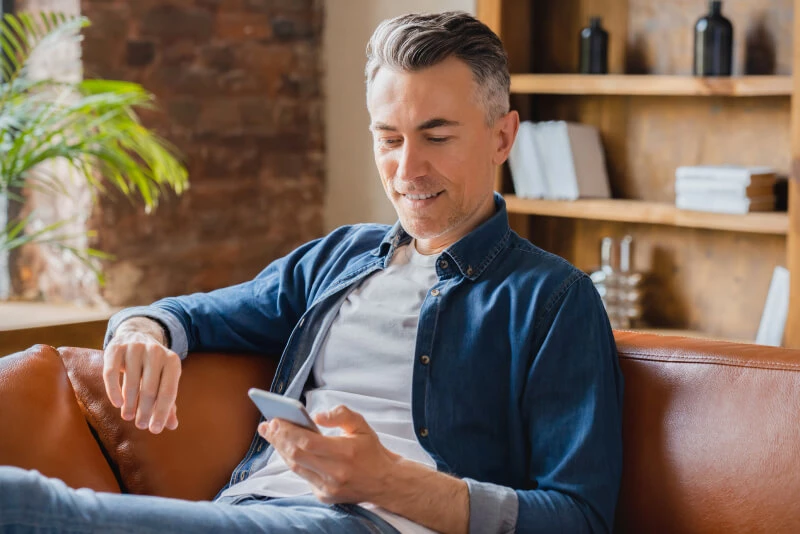 A man sitting in his chair and looking at his mobile device