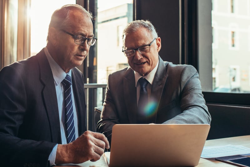 Two older gentlemen looking at a laptop