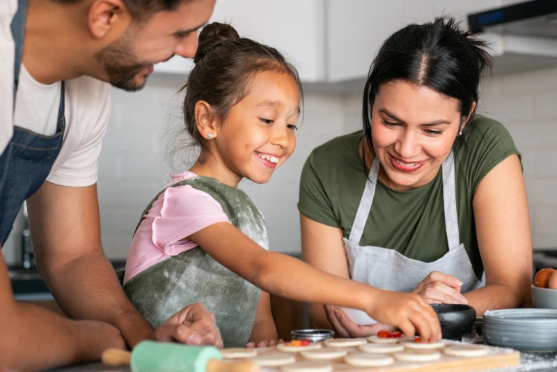 A close-up image of a young family of three baking cookies