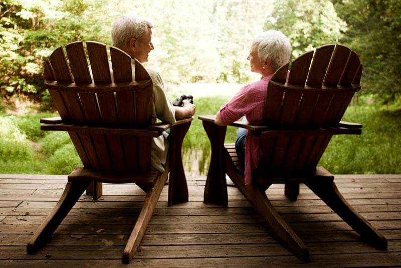 Retired couple relaxing in deck chairs discussing their retirement planning options