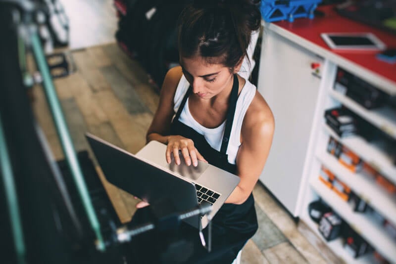 A young business owner holds her laptop while researching fraud protection for her company