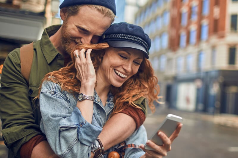 A couple laughing on a street corner