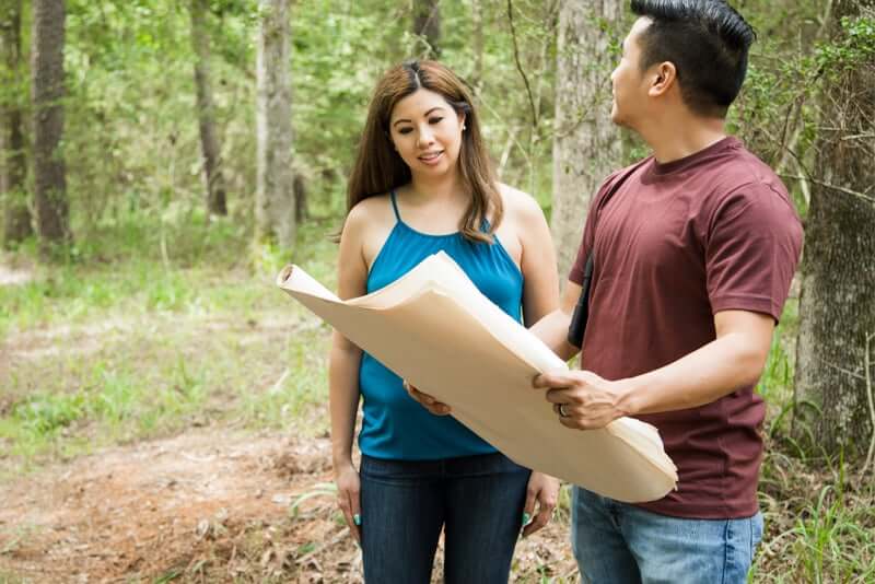 A couple with some blue prints imaging what their home could be on a piece of land