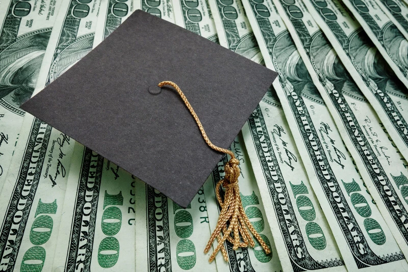 A graduation cap on top of money