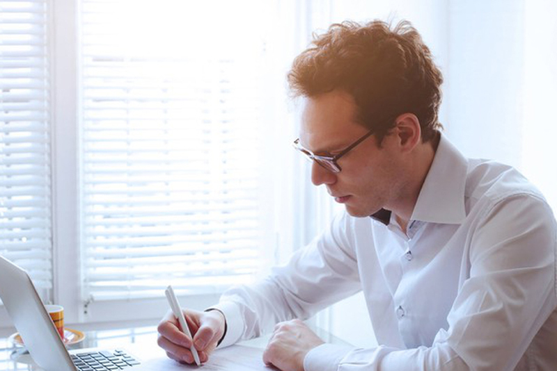 A man taking notes at his laptop