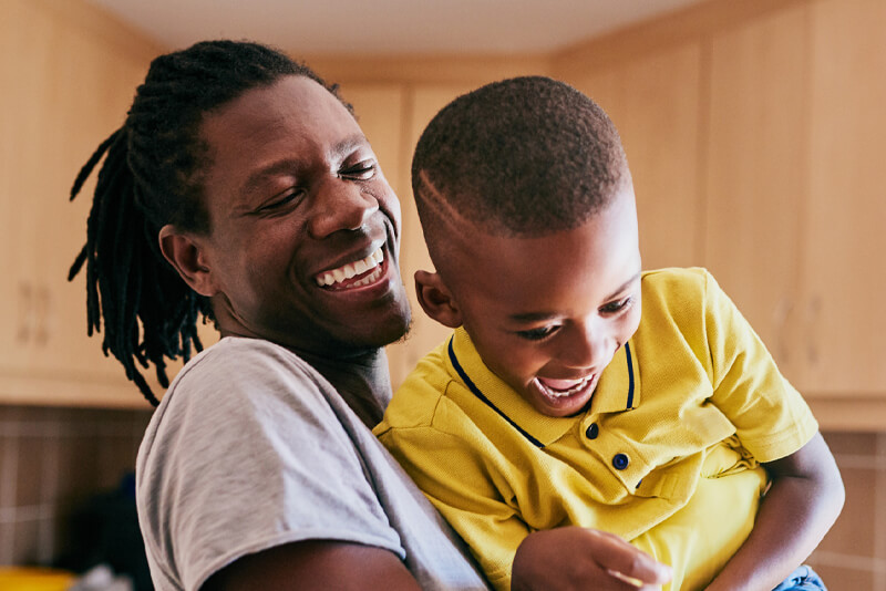 A dad and son playing in their kitchen