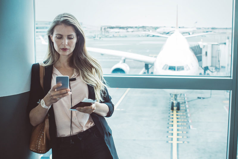 A businesswoman on her phone at an airport helps protect her business from cyber-attacks with Fraud Mitigation tools