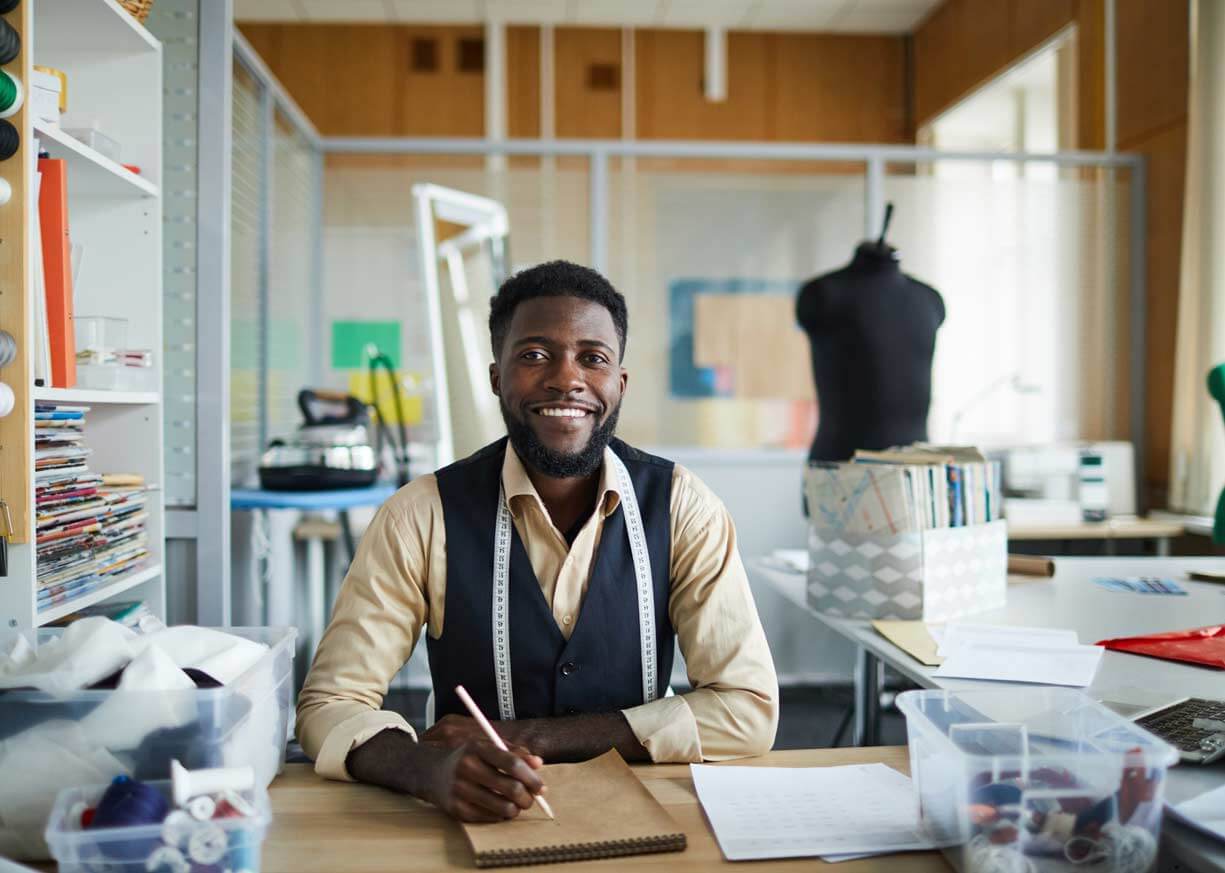 A fashion designer and business owner smiles confidently because he secured a small business loan